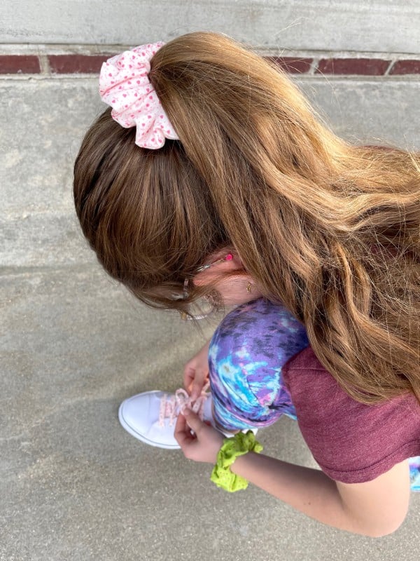 A Girl with a GO! Hair Scrunchie and Tying Her New Shoelaces
